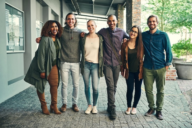 A diverse group of Americans smiling and standing together near a community health center in a vibrant urban neighborhood.