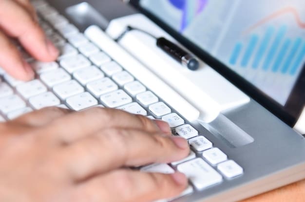 A close-up shot of a hand typing on a keyboard, with charts and graphs reflecting economic data visible in the background. Focus is on the interaction between human labor and technological analysis of economic trends.