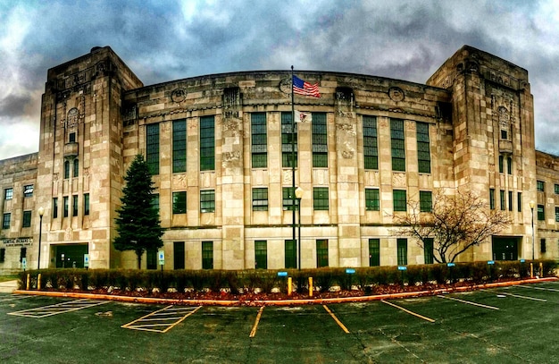 A photo illustrating the Federal Reserve headquarters in Washington, D.C., with a focus on the building's architecture and the American flag waving in the background. The sky is clear and blue, symbolizing stability and authority.