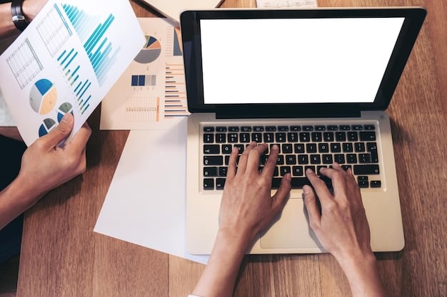 A close-up shot of a person's hands typing on a laptop, with charts and graphs related to unemployment statistics displayed in the background on the laptop screen, symbolizing data analysis and research in the context of job market reports.